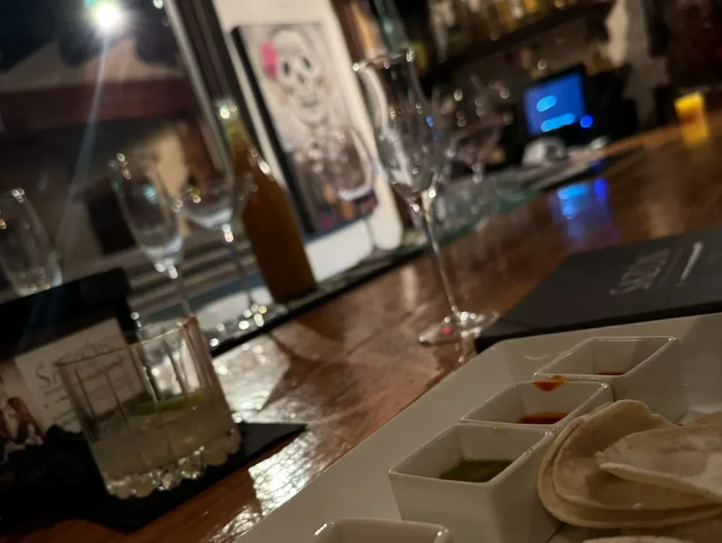 bar with glassware and sugar skull painting on the wall